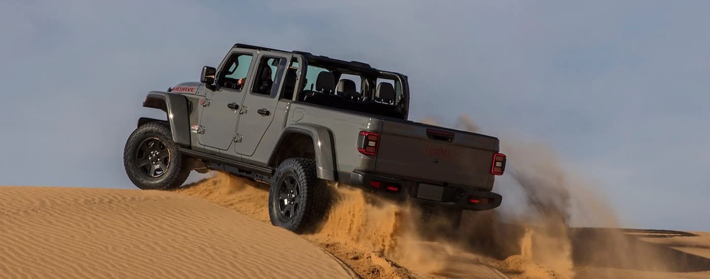 A grey 2023 Jeep Gladiator Mojave is shown from the rear at an angle after leaving a Jeep dealer.