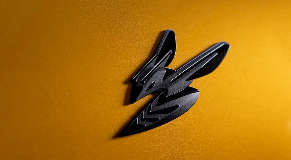 A close-up of the Hornet badge on a yellow 2024 Dodge Hornet GT.