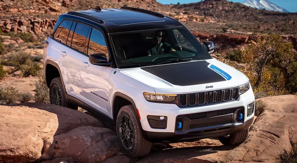 A black and white 2024 Jeep Grand Cherokee 4xe is shown parked off-road in a desert.