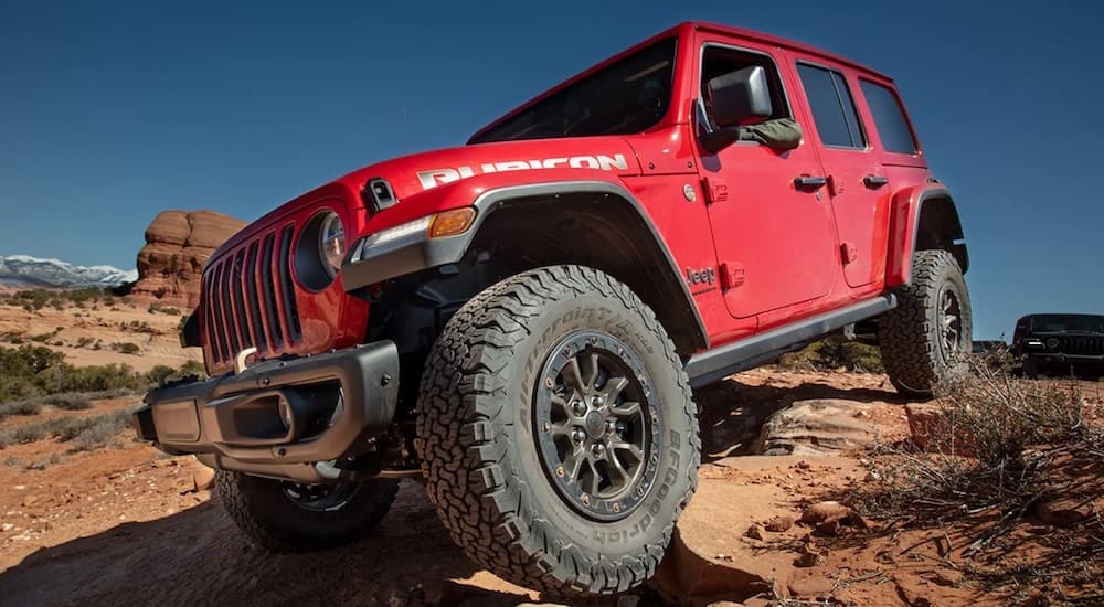 A red 2023 Jeep Wrangler Rubicon is shown from the front at an angle after leaving a used Jeep dealer.