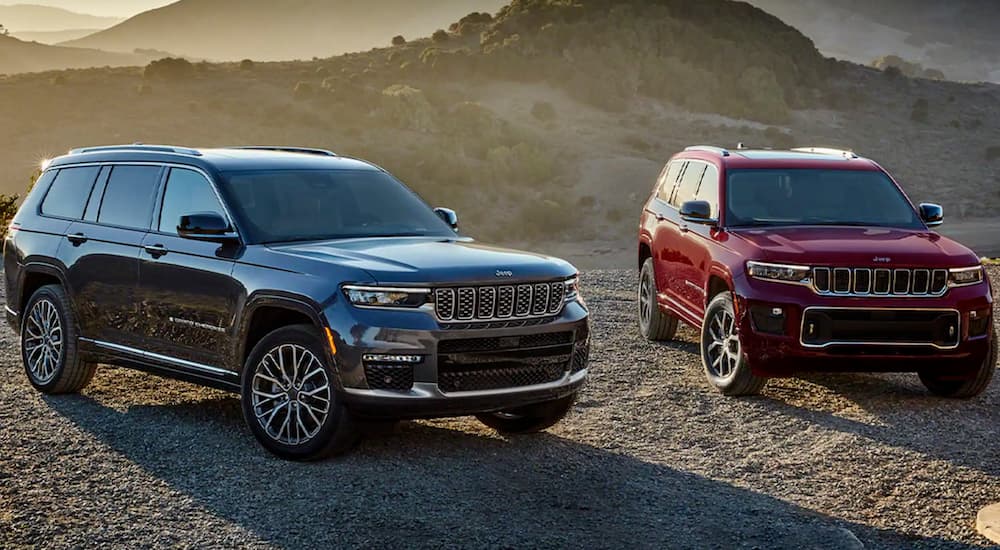 A grey and a red 2022 Jeep Grand Cherokee are shown parked off-road after leaving a used Jeep dealer.