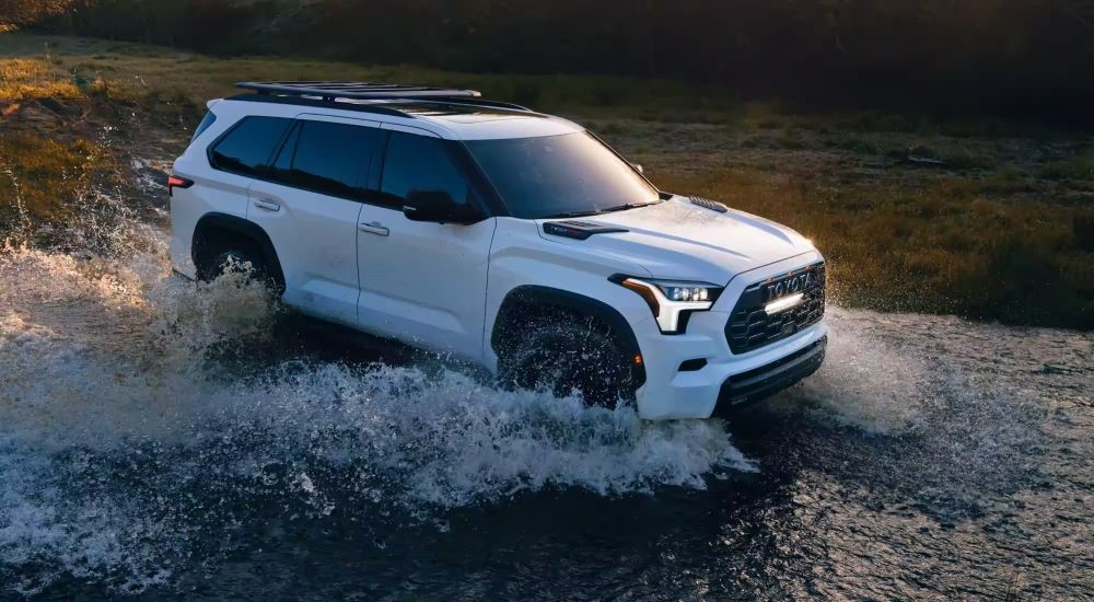 A white 2023 Toyota Sequoia TRD fording a shallow river.