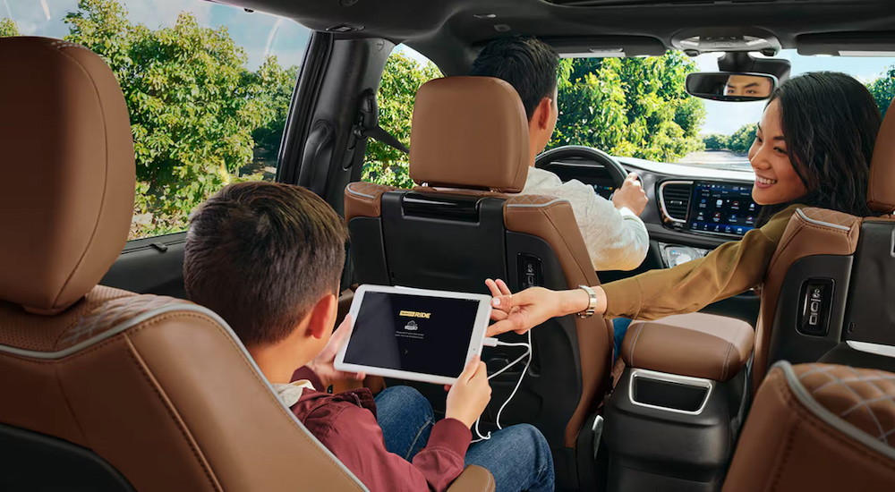 A kid using a tablet in the back seat of a 2024 Chrysler Pacifica Pinnacle.