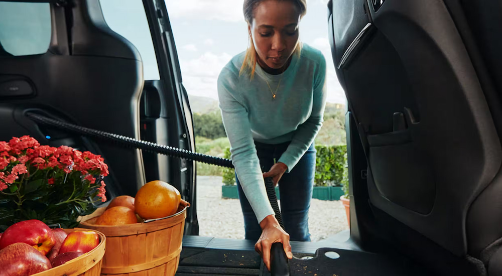 A woman using the integrated vacuum in a 2024 Chrysler Pacifica at a Chrysler dealer near Decatur.