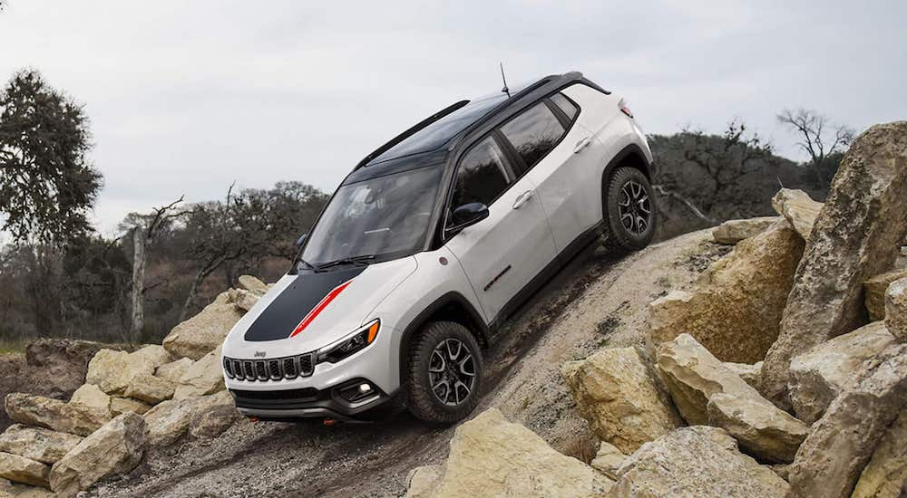 A white 2025 Jeep Compass Trailhawk is shown from the front at an angle.