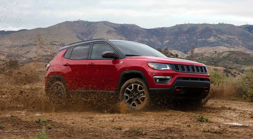 A red 2025 Jeep Compass Trailhawk is shown from the front at an angle.