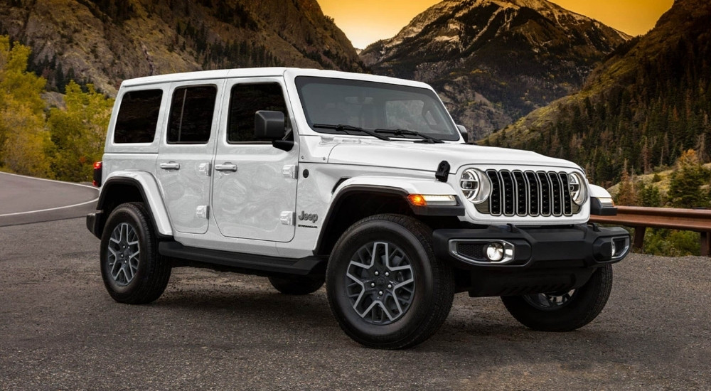 A white 2025 Jeep Wrangler Unlimited Sahara parked on gravel.