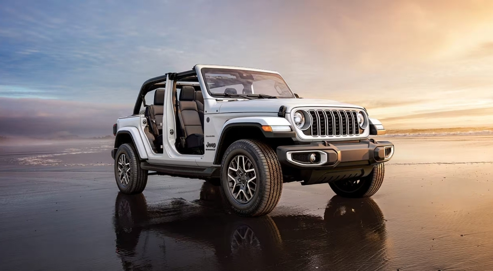 A white 2025 Jeep Wrangler Unlimited Sahara parked on a shore.