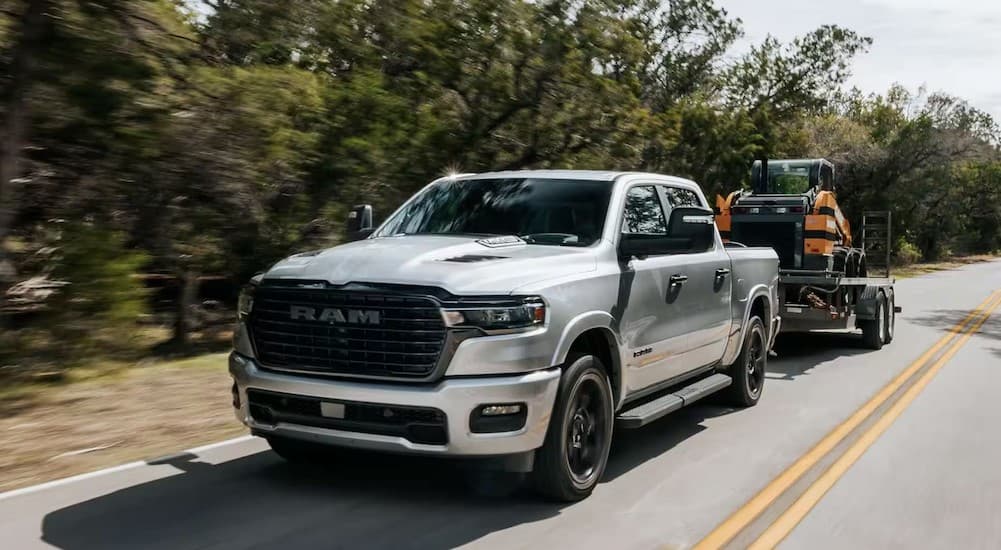 A silver 2025 Ram 1500 towing a trailer.