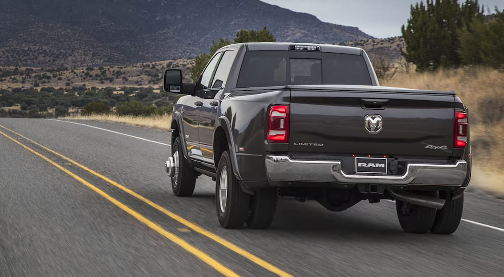 Rear of a black 2025 Ram 3500 Limited driving down an open road.