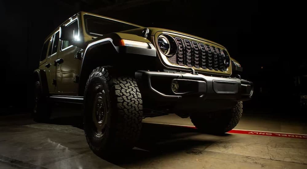 A green 2025 Jeep Wrangler for sale near Decatur parked in a dark room.