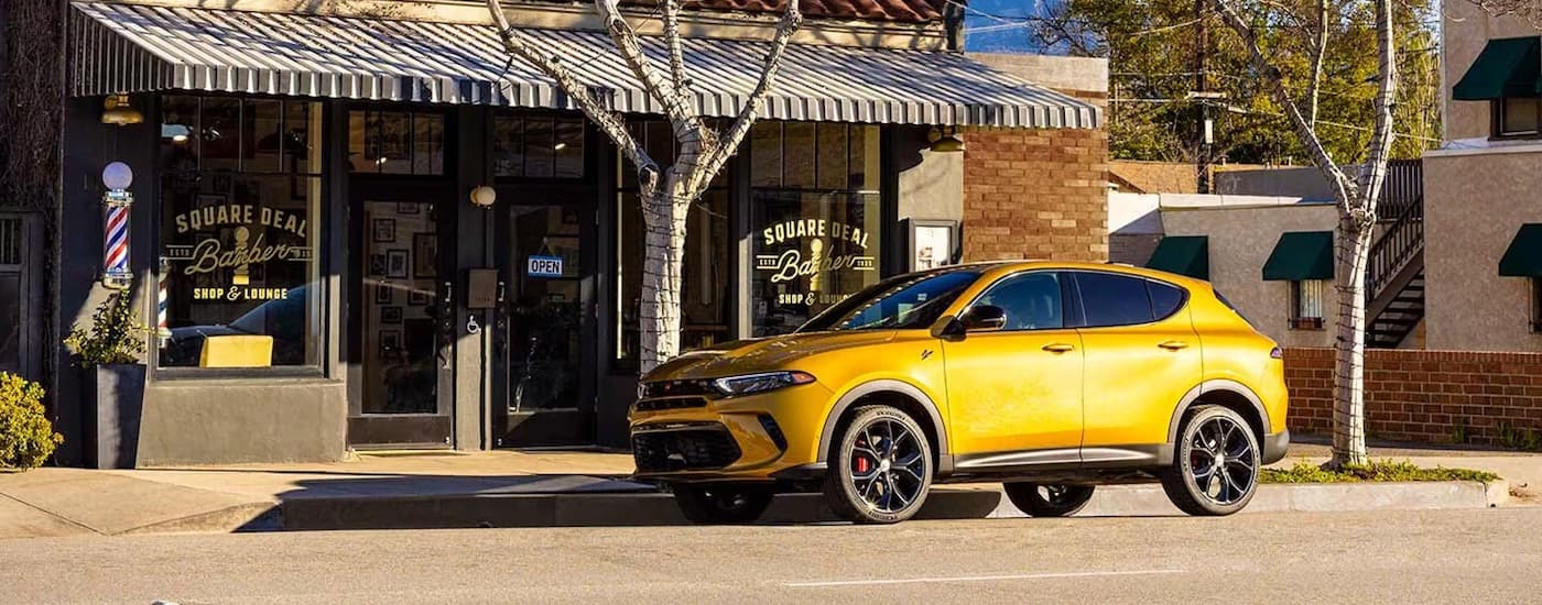 A yellow 2024 Dodge Hornet parked outside a local barber shop.