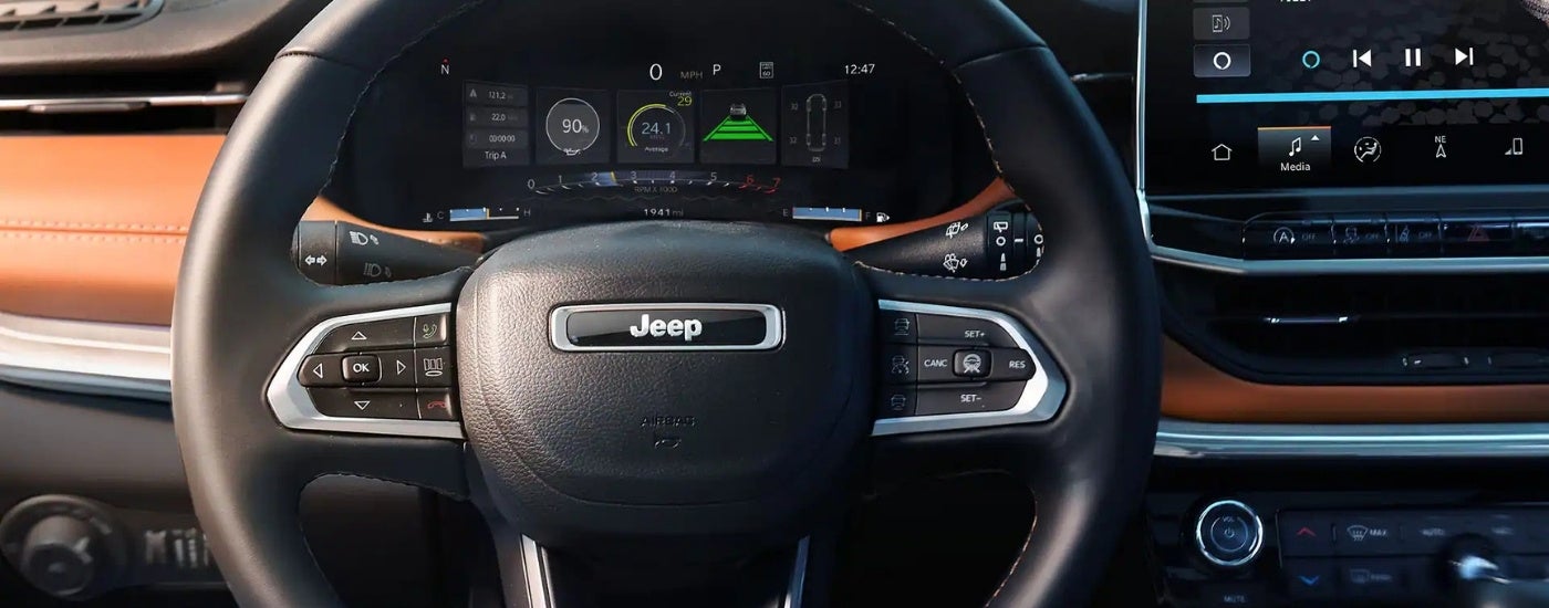 The black interior of a 2025 Jeep Compass is shown from the driver's seat.