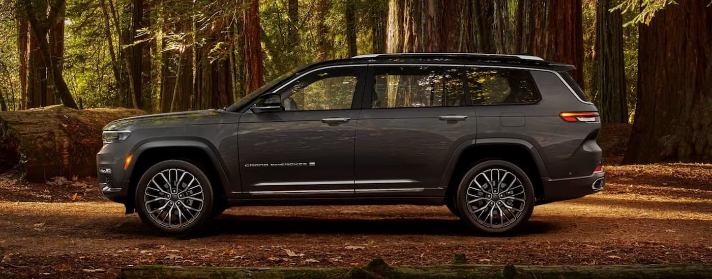 A grey 2024 Jeep Grand Cherokee is shown from the side while parked off-road.