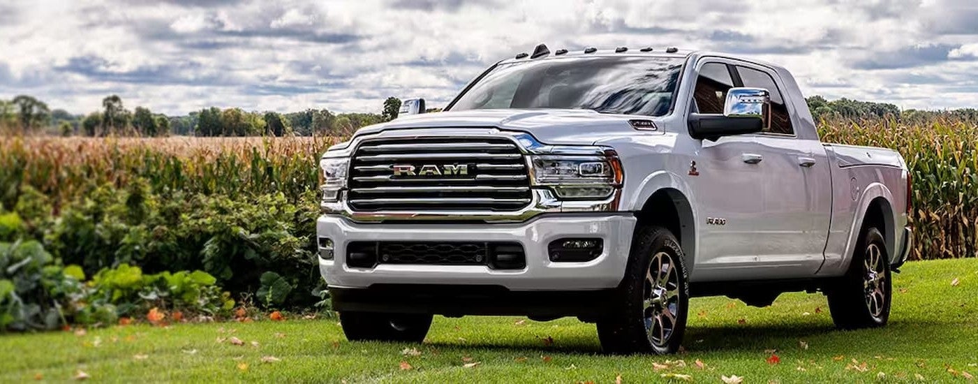 A white 2024 Ram 2500 parked off-road on a grass field and angled left.