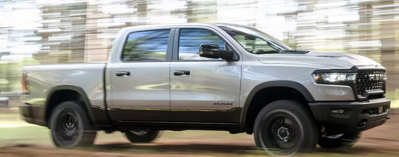 White 2024 Ram 1500 driving through a forest from a Ram dealer near Clinton.