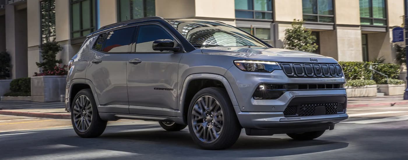 A silver 2022 Jeep Compass driving through a city.