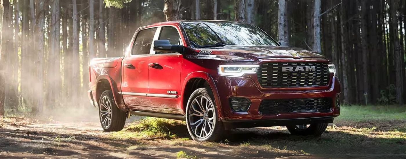A red 2025 Ram 1500 parked off-road on grass